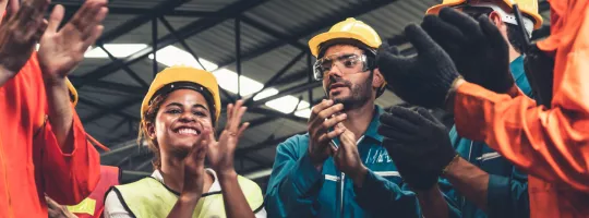 A photograph of construction workers clapping in a circle