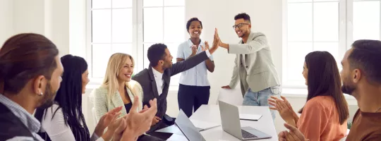 Two employees high fiving over a table