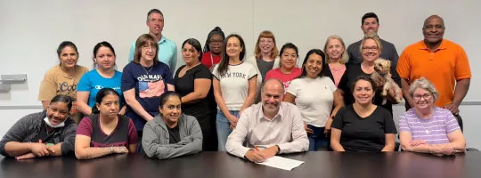 Henry Benamram signing the United Nations Women's Empowerment Principles surrounded by Inspirus employees.