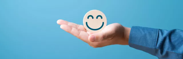 A hand holding a smiling face